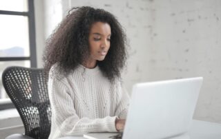 A woman smiling while working on her laptop in a bright, modern office, symbolising calm and balanced productivity. Achieving a work life balance