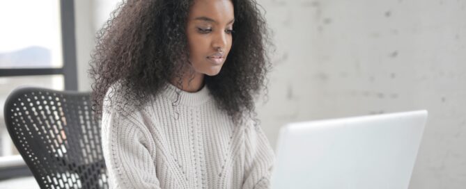 A woman smiling while working on her laptop in a bright, modern office, symbolising calm and balanced productivity. Achieving a work life balance